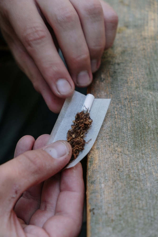 Ruce balící cigaretu, detail na tabák a papírek